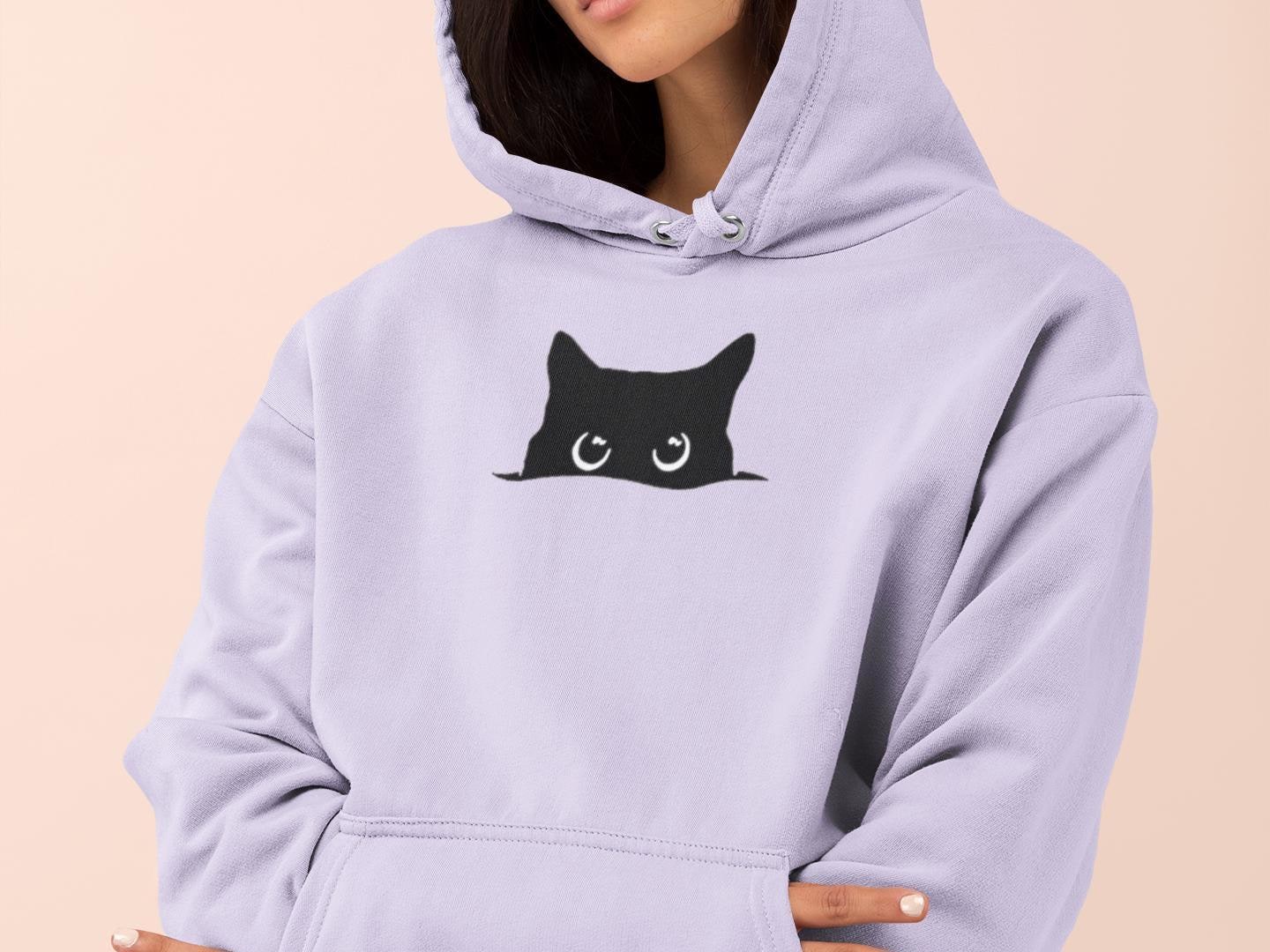 a woman wearing a purple sweatshirt with a black cat on it