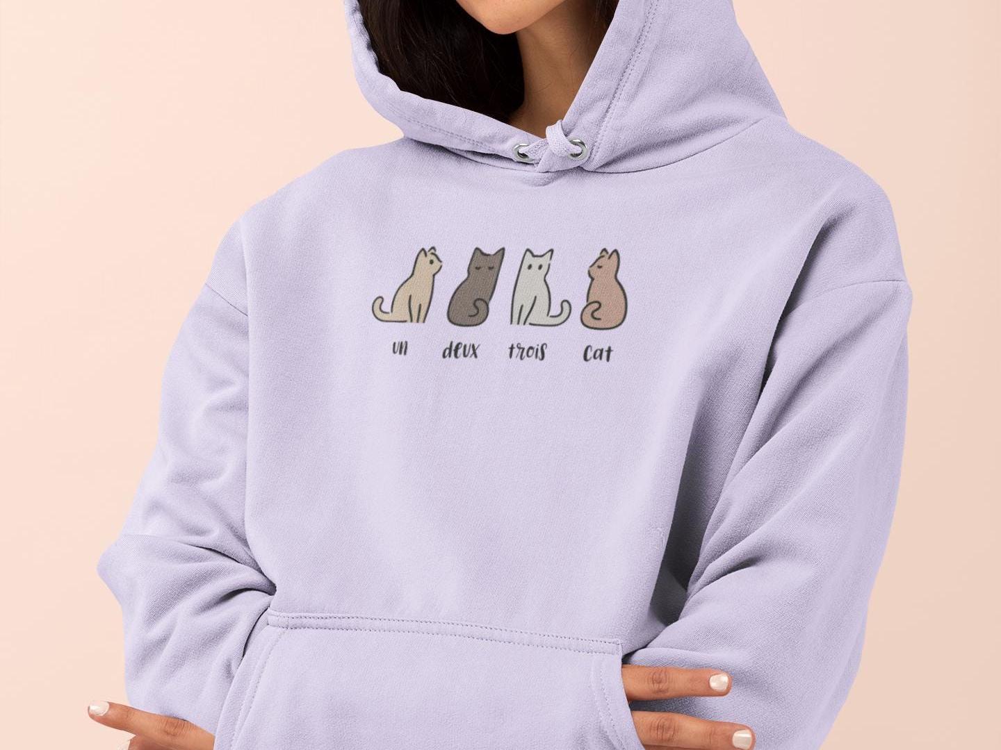 a woman wearing a purple hoodie with cats on it