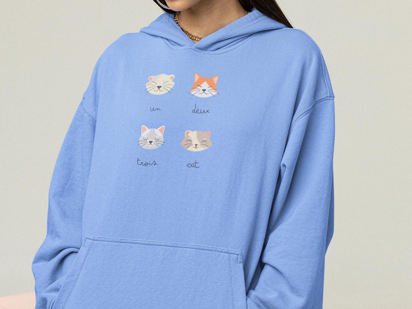 a woman wearing a blue hoodie with cats on it